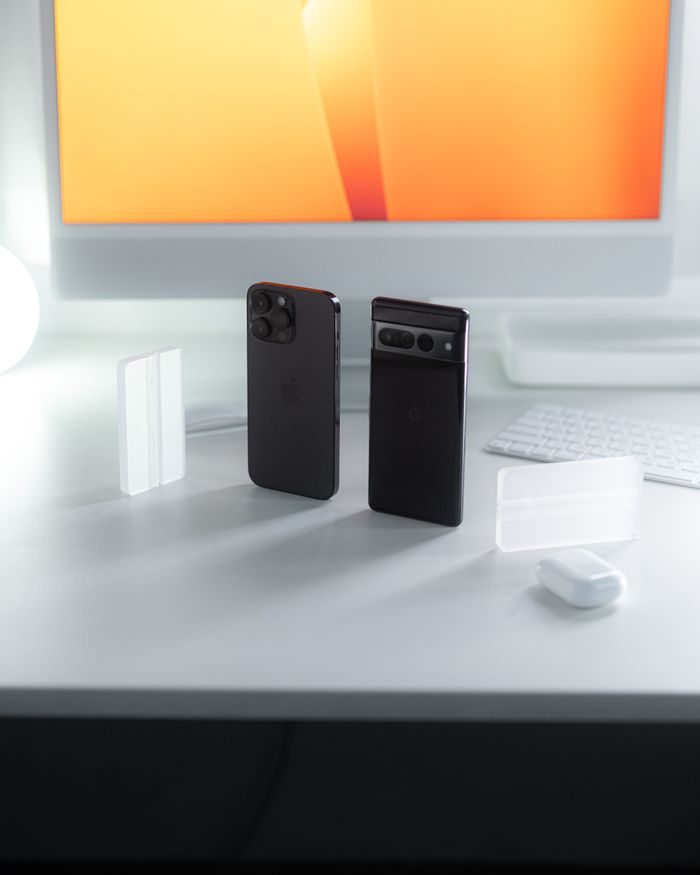 A sleek display of two smartphones against a glowing monitor on a minimalist desk.